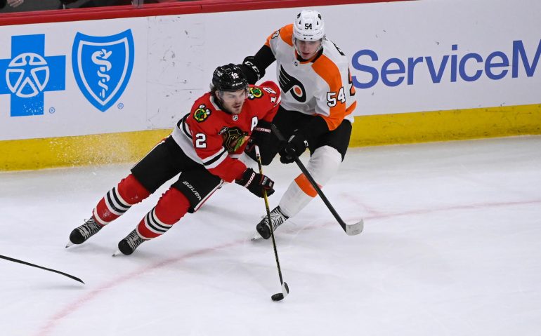 Apr 25, 2022; Chicago, Illinois, USA; Chicago Blackhawks left wing Alex DeBrincat (12) moves the puck past Philadelphia Flyers defenseman Egor Zamula (54) during the second period at  the United Center. Mandatory Credit: Matt Marton-USA TODAY Sports