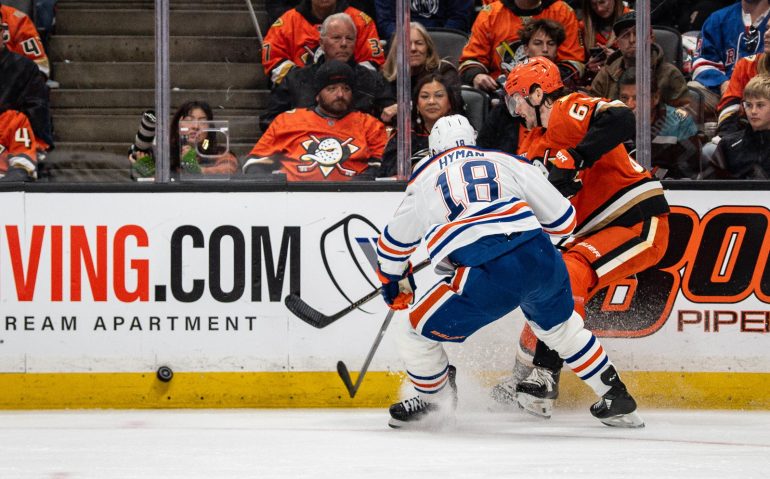 Apr 26, 2026; Anaheim, California, USA; Edmonton Oilers left wing Zach Hyman (18) contends for the puck against Anaheim Ducks defenseman Jacob Trouba (65) during the first period in game four of the first round of the 2026 Stanley Cup Playoffs at Honda Center. Mandatory Credit: Corinne Votaw-Imagn Images