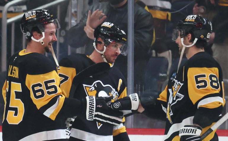 Mar 30, 2025; Pittsburgh, Pennsylvania, USA;  Pittsburgh Penguins defenseman Erik Karlsson (65) and center Sidney Crosby (middle) and defenseman Kris Letang (58) celebrate after defeating the Ottawa Senators in overtime at PPG Paints Arena. Mandatory Credit: Charles LeClaire-Imagn Images