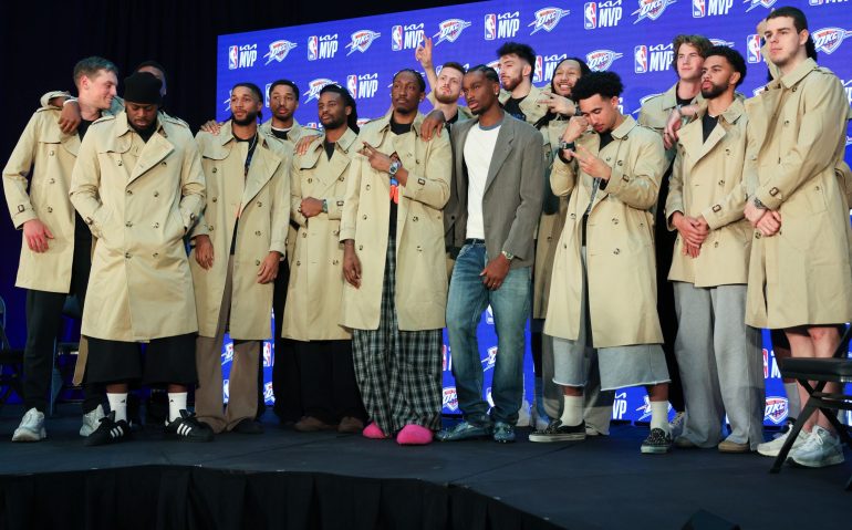 Oklahoma City Thunder guard Shai Gilgeous-Alexander, center, poses with teammates in Burberry trench coats he bought during a news conference after he was named the NBA basketball MVP, Sunday, May 17, 2026, in Oklahoma City. (AP Photo/Nate Billings)